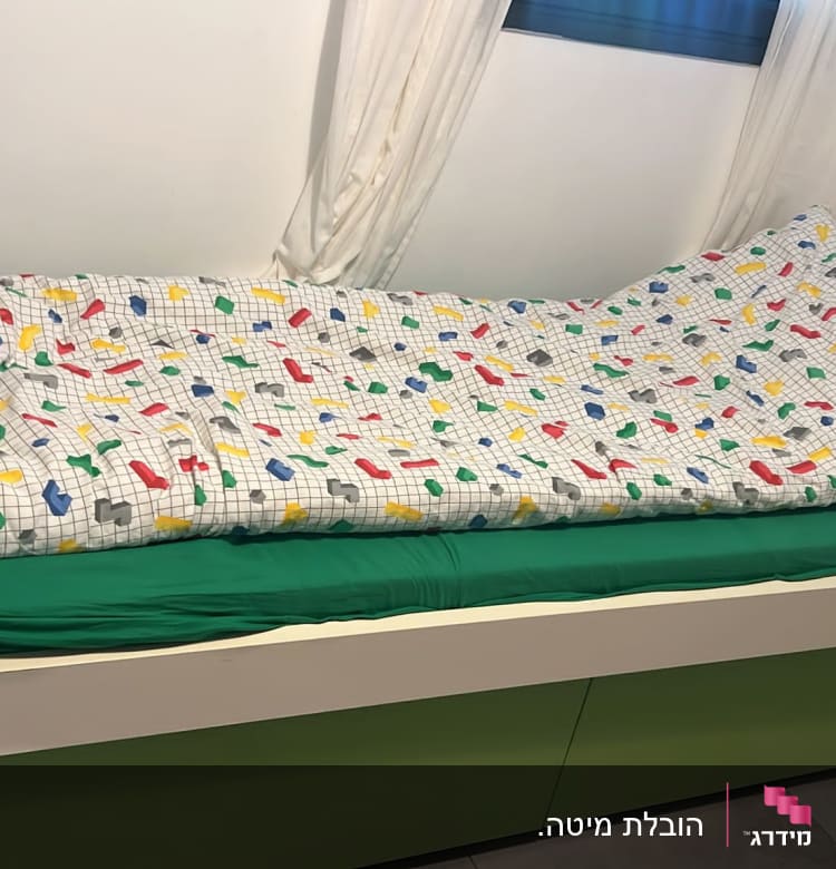מיטה עם מצעים צבעוניים על רקע קיר לבן